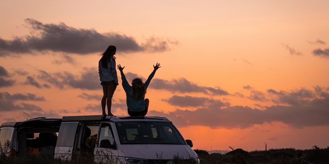 Zwei Freunde freuen sich beim Camping über Sonnenuntergang
