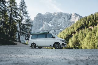 Ein VW Camper steht beim Camping in Albanien vor einer Bergkulisse.