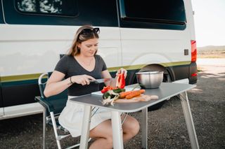 Frau isst vor Camper